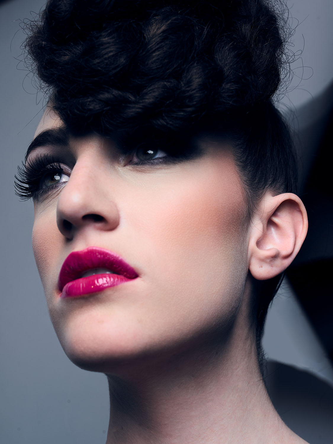 High-fashion beauty close-up of Renee Vermeuel with voluminous textured hair, dramatic lashes, and glossy bold pink lips in a studio setting