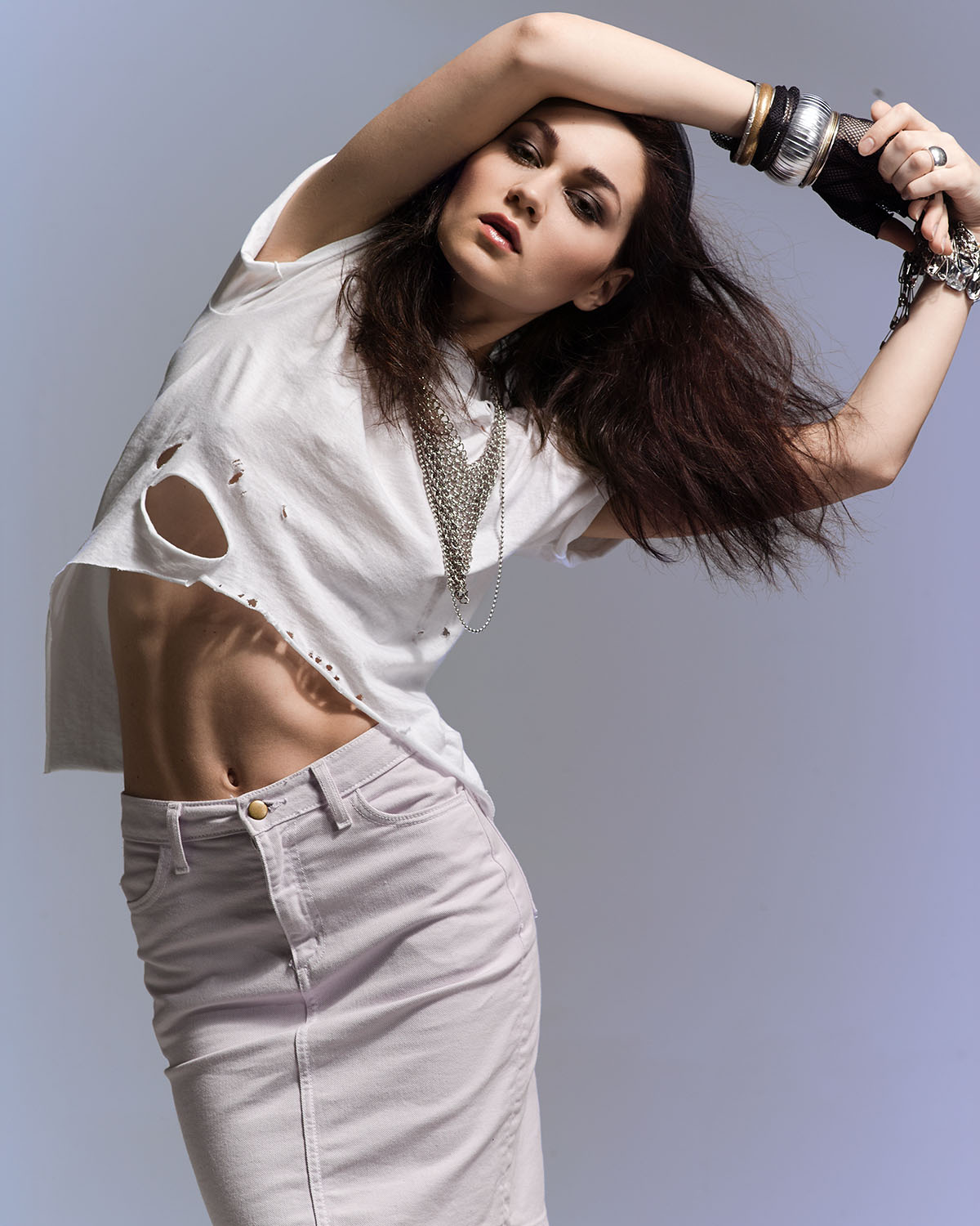Studio fashion editorial portrait of model Blaga in a distressed white tee, denim mini skirt, and layered silver chain necklaces, hair styled by DJ Quintero — Jason Guffy Photography, Brooklyn
